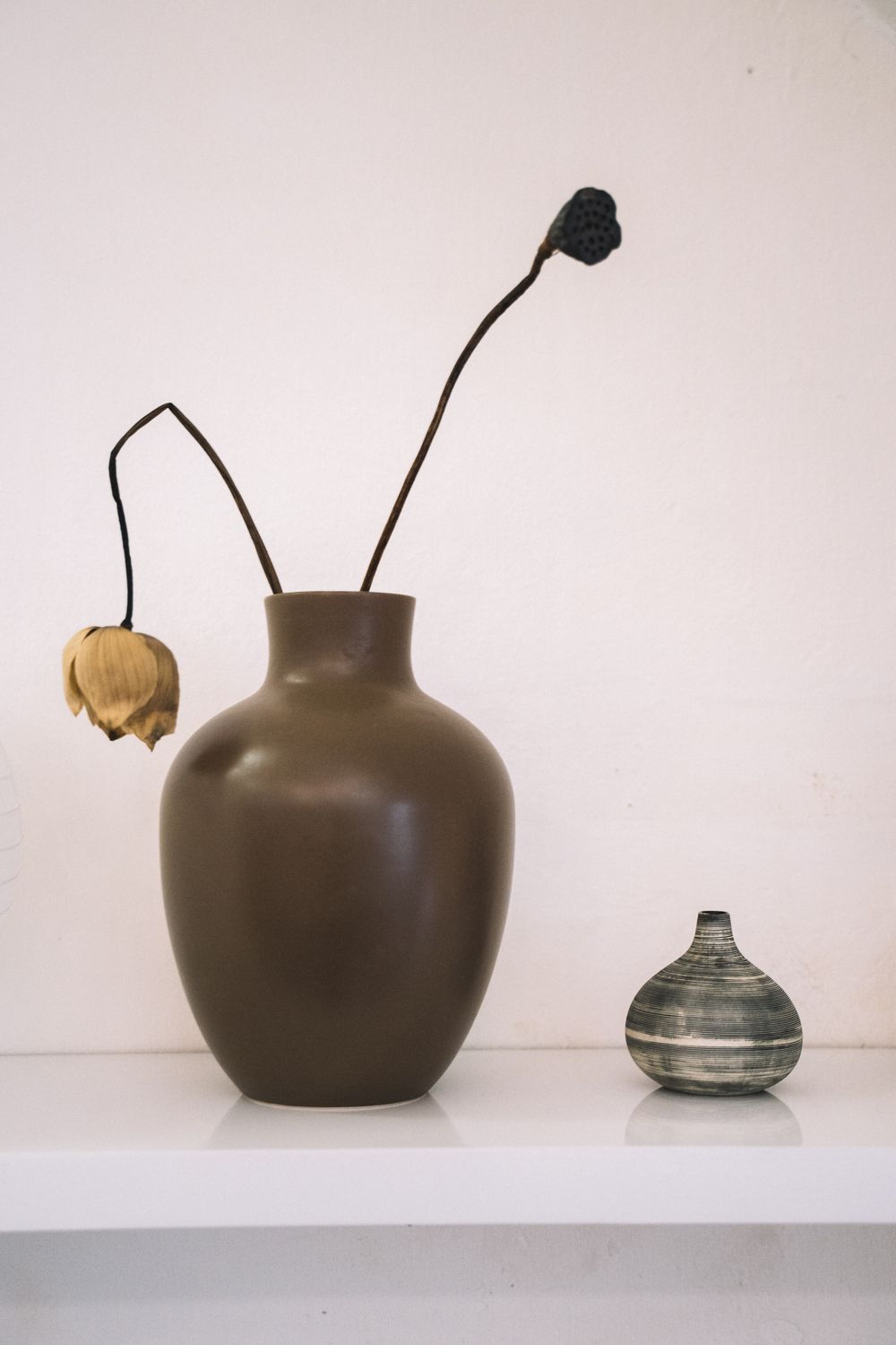 A tall pitcher with celadon glaze dripping over raw clay.
