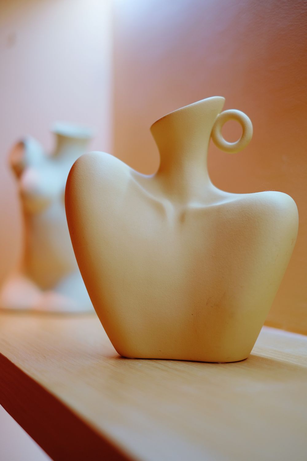 A slim white porcelain bud vase holding a single stem.